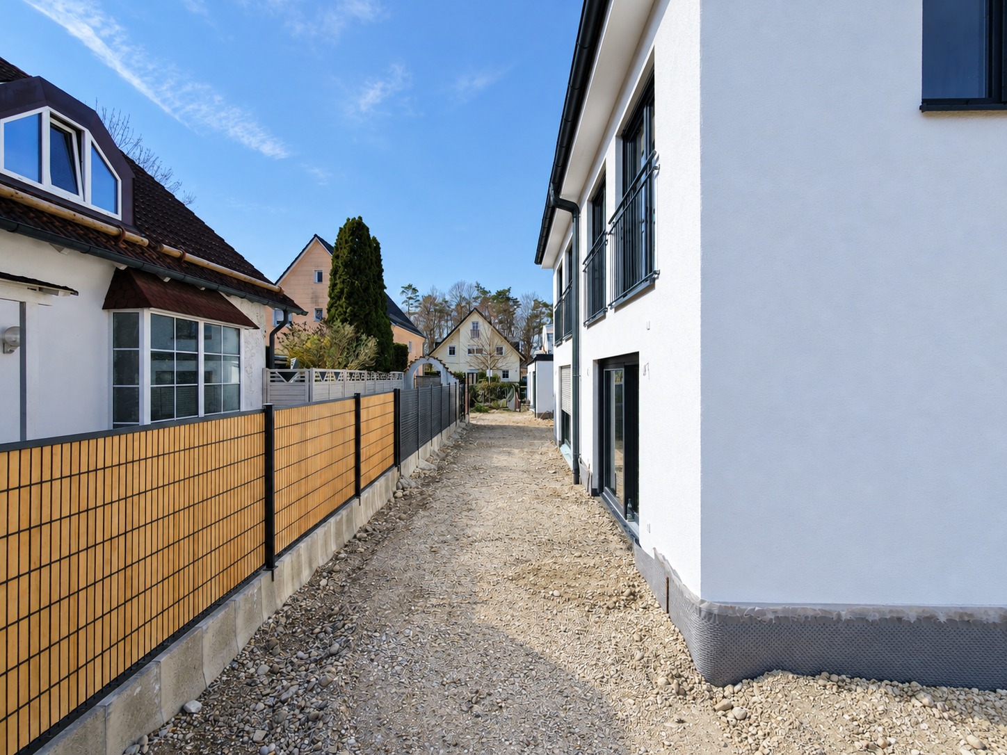 Baufortschritt mit montierter Sichtschutzanlage und noch unbefestigter Fläche am Haus in München-Aubing