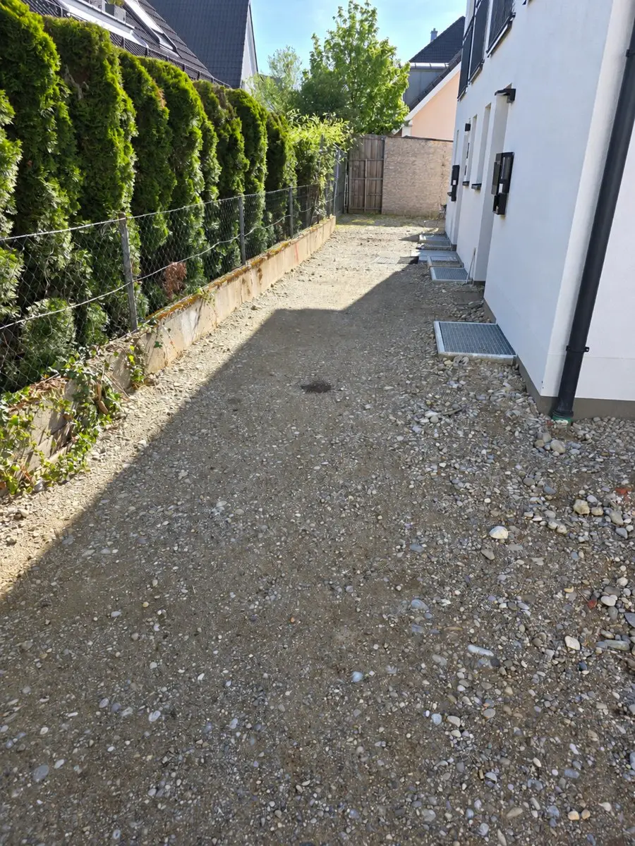 Hauszugang mit Kiesuntergrund und altem Grenzzaun vor den Gartenbauarbeiten in München-Aubing